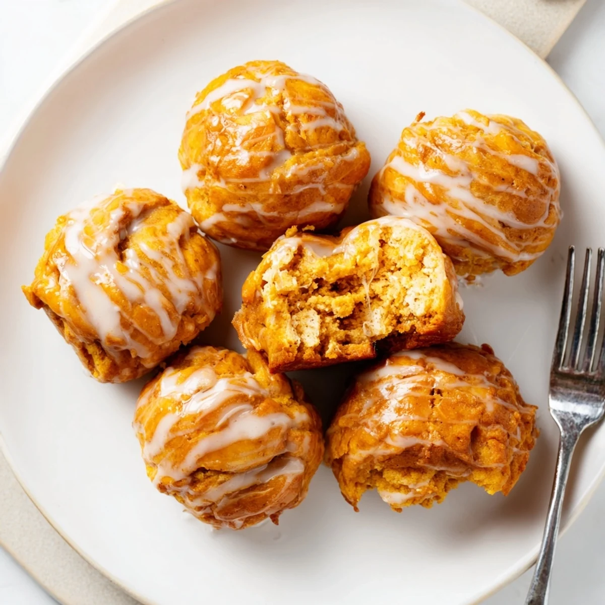 Delicious maple bourbon flaky pumpkin muffin balls, drizzled with rich glaze, ideal for fall.