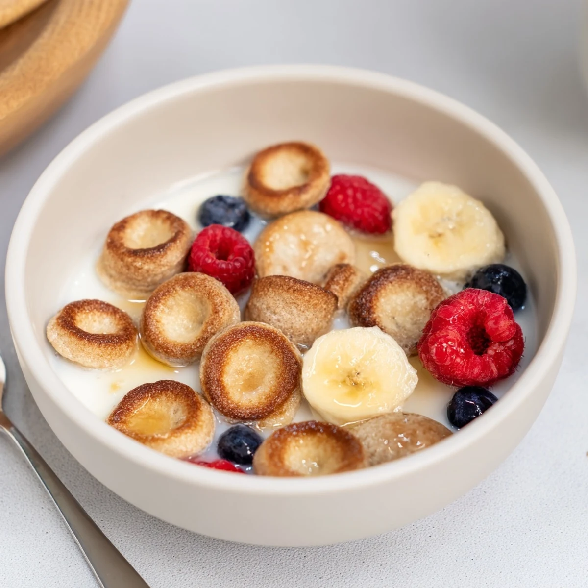 Adorable mini pancake cereal served with fresh fruit and syrup for breakfast.  