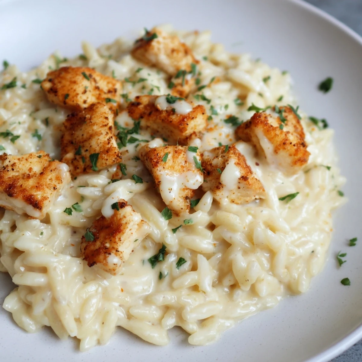 This warm bowl of Cajun Chicken Alfredo Orzo steams with Cajun spice and savory Parmesan cheese.