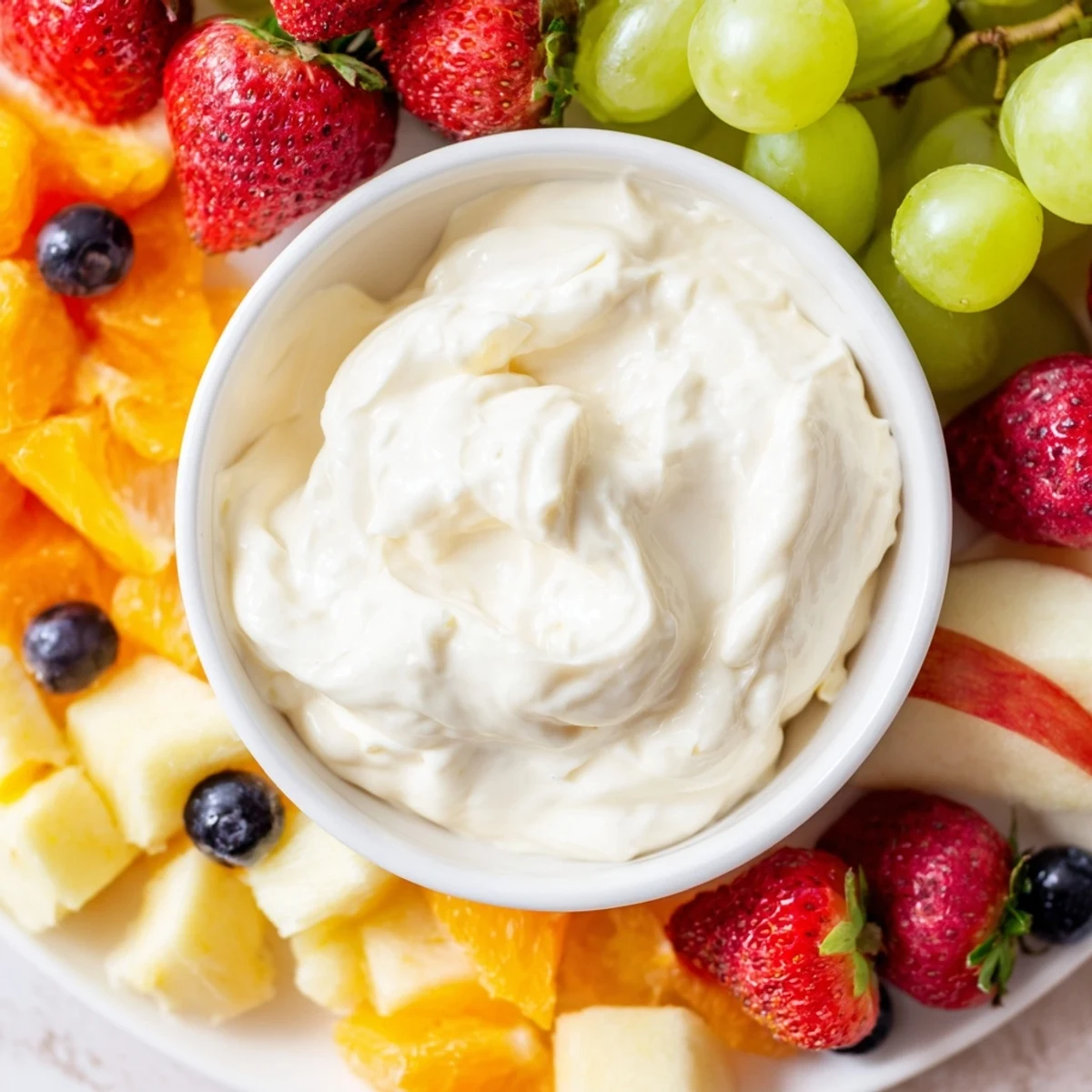 Creamy cream cheese fruit dip in a bowl surrounded by colorful, appealing fresh fruit for dipping.