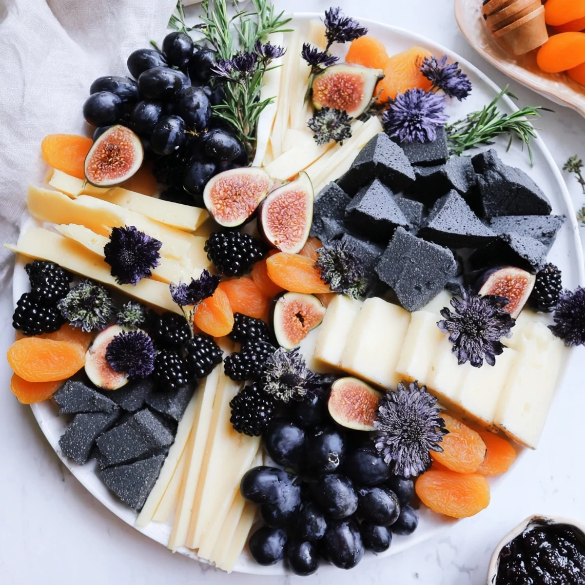A creatively arranged Ghostly Outline Halloween Charcuterie Board with dark cheeses and fruits.