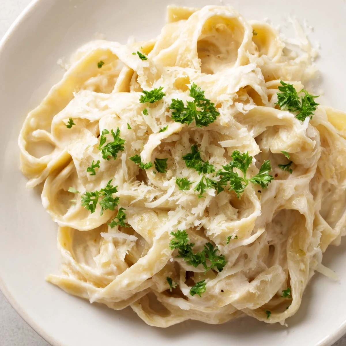 A visually appealing photo of Pasta Alfredo Cottage Hack, swirled on a plate and garnished with parsley.