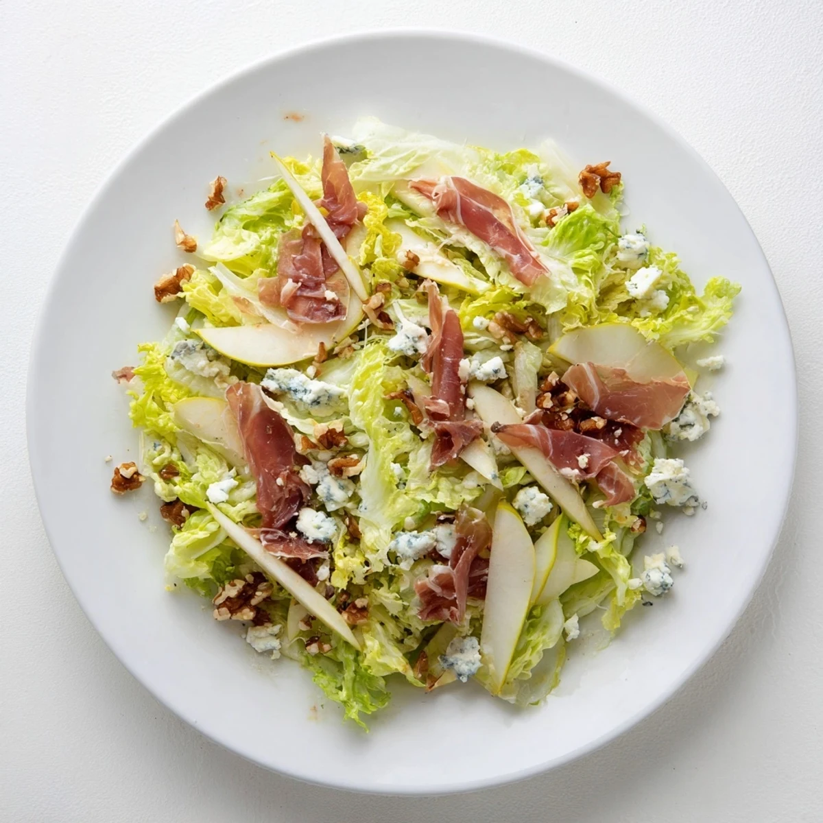 Crisp frisée, juicy pear slices, and crumbled blue cheese tossed with salty prosciutto shards for an elegant salad.