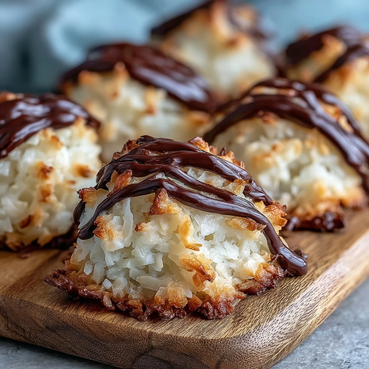 Freshly baked Vegan Coconut Macaroons with dark chocolate drizzle sit golden brown on a cooling rack.