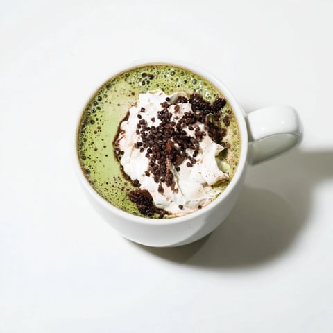 Steaming Collagen Peppermint Mocha Matcha Latte, a vibrant green and cocoa-brown drink topped with whipped cream.