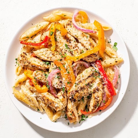 Sliced Cajun chicken pasta with creamy sauce, peppers, and parsley garnish, delicious and flavorful.