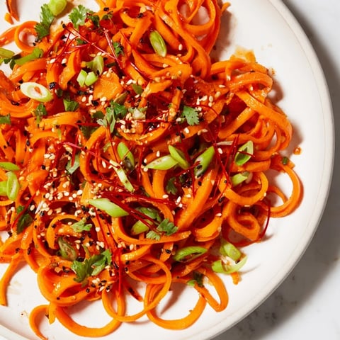 Vibrant Carrot Ribbon Salad Asian-Style tossed with a savory sesame dressing and toasted seeds, ready to eat.