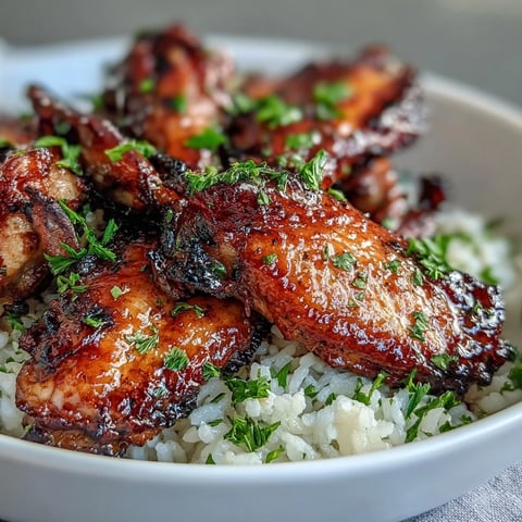 Golden-brown Oven-Baked Honey Garlic Chicken Wings glazed in sticky sauce, served over fluffy, buttery rice with fresh parsley garnish. 