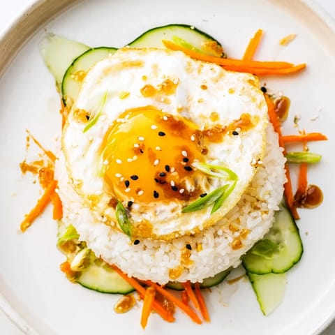 This crispy egg rice bowl has a beautiful fried egg and colorful veggie toppings.