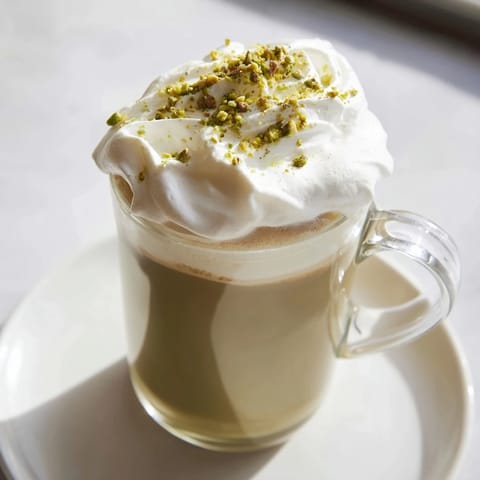Steaming pistachio milk layered over espresso, forming a delicious Pistachio Latte Cloud beverage.