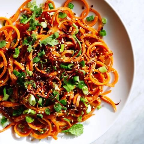Freshly tossed Carrot Ribbon Salad Asian-Style, with visible green onions and red chili, looks so delicious.