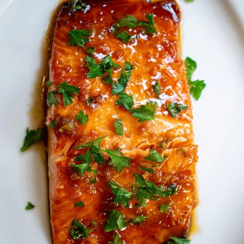 Tender salmon fillets brushed with a rich honey garlic butter glaze, served hot with lemon wedges on a rustic wooden table.  