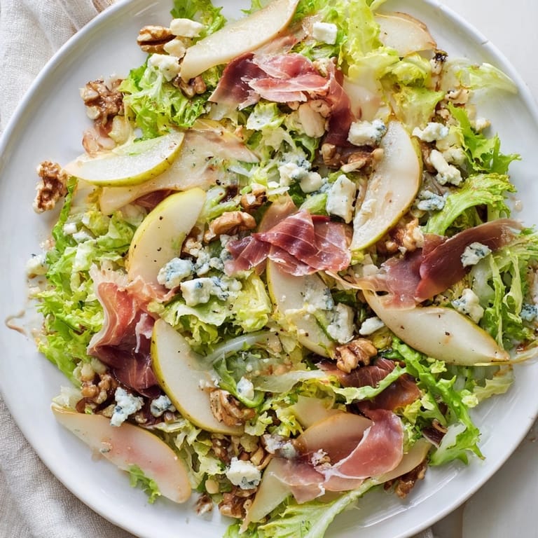 An overhead view of the pear, blue cheese, and frisée salad, topped with crunchy baked prosciutto and a light vinaigrette.