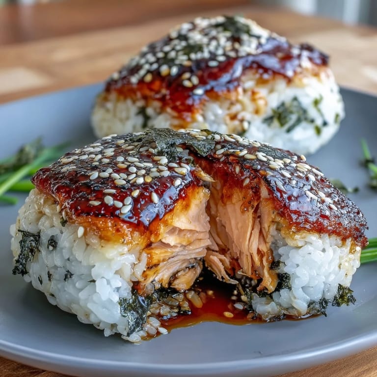 Warm Grilled Salmon Onigiri: Japanese rice triangles stuffed with flaky grilled salmon, wrapped in nori and sprinkled with sesame seeds.