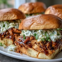 1. Pulled BBQ Chicken Sandwiches with tender shredded chicken in smoky barbecue sauce on soft brioche buns.  